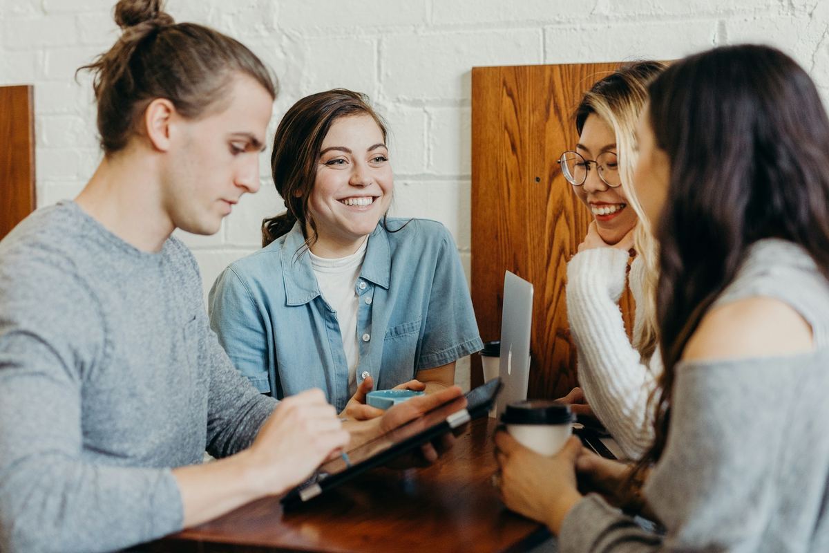 A diverse group of young people laughing together around a table