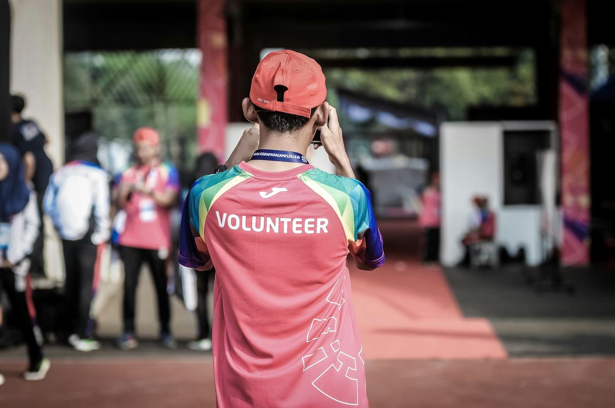 A volunteer in a bright shirt helping at a community event