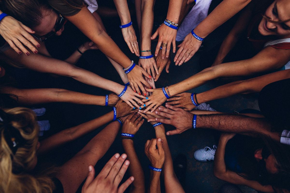 A circle of people joining hands together in support